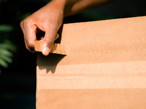 Person Opening a Cardboard Box With a Hand in Daylight