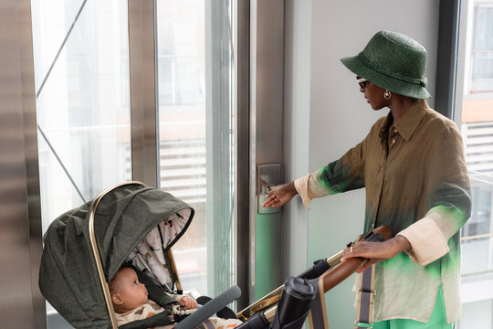 Woman With Stroller Calling Elevator in Urban Building