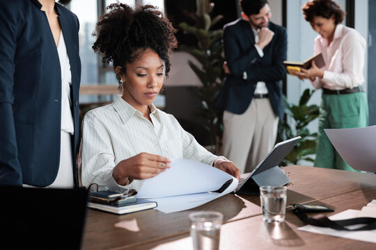 Business meeting, woman reviews documents at a conference table.