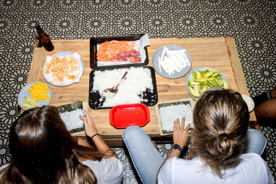 UGC Overhead view of friends making sushi at home with direct flash
