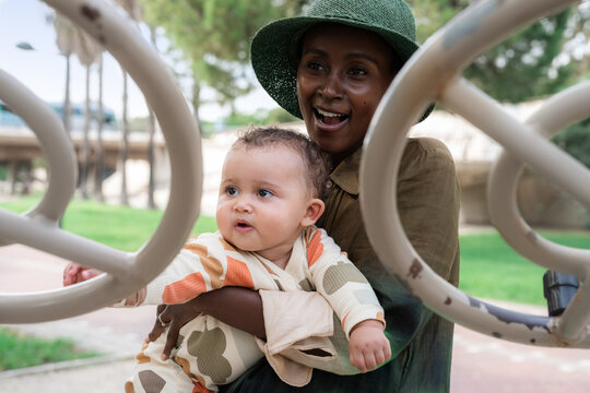 Mother Holds Baby While Playing at Park on Sunny Day
