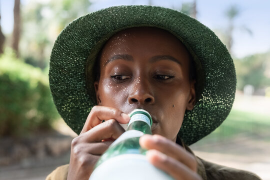 Woman Drinks From a Bottle in a Park During the Day