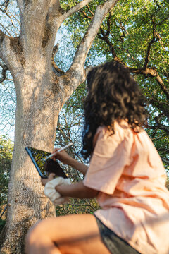 Woman drawing on digital tablet outdoors in nature