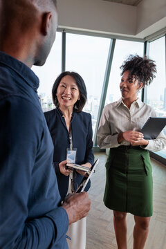 Professionals in discussion with speaker badge in modern office