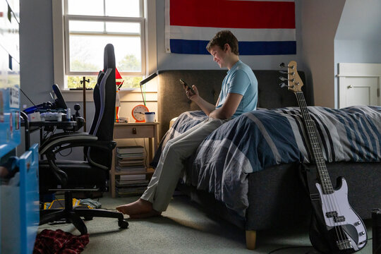 Casual Teenager looking at cell phone bedroom 