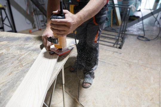 Carpenter works with hand-milling machine