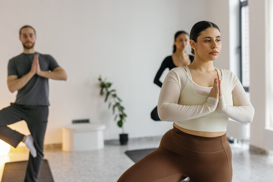 Multiethnic people practicing yoga in Anjali Mudra with Vrksasana pose