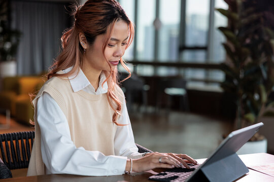 Woman with dyed hair works on a digital tablet.