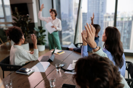 Business meeting with hands raised in agreement.