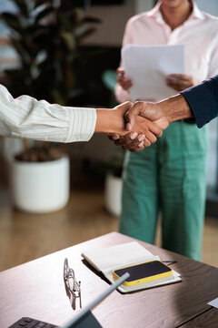 Business handshake over a desk with phone and notebook.