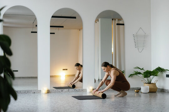 Side view of woman spreading sports carpet before practicing yoga