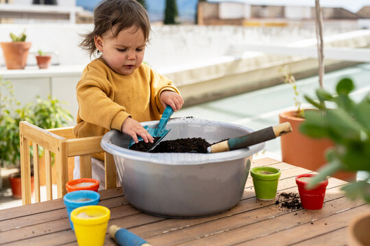 Baby Playing With Soil In Learning Tower On Terrace