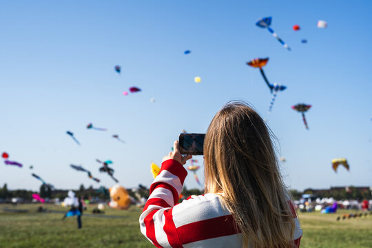 Young woman taking photos of kites 