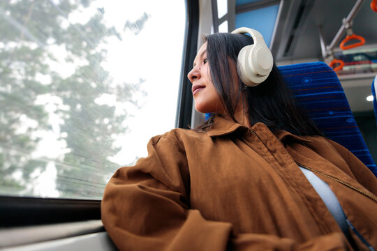 Woman with headphones looks out window