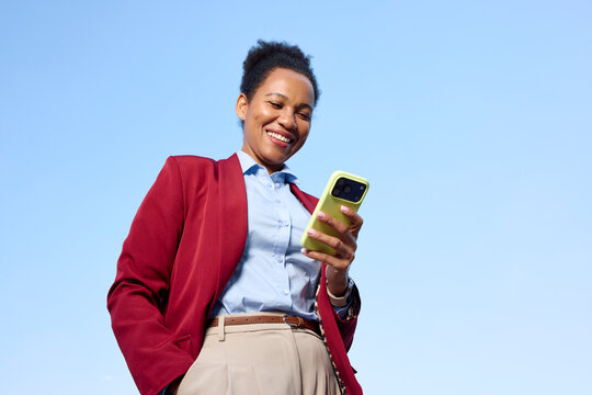 Formally dressed woman uses her phone against the blue sky