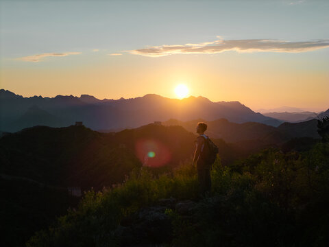 Solo traveler watching the sunrise over the Great Wall of China