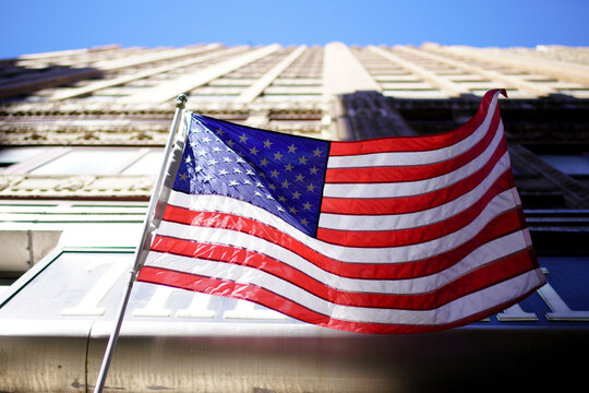 Iconic US flag contrasts with geometric building design in sunlight