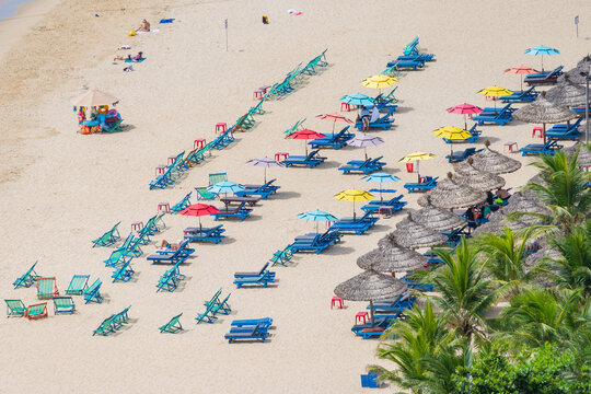 Colorful beach chairs and umbrellas scattered along a sandy beach