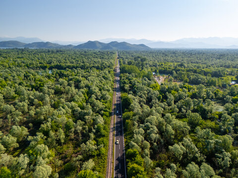 Aerial shot Road Through Green Forest With Mountains in the Distance