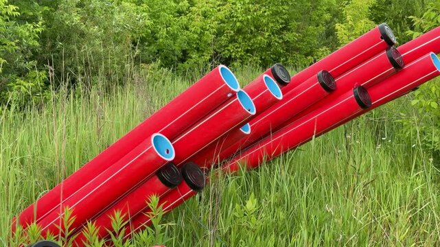 Colored pipes arranged. Plastic pipes with fittings in green field ready for installation. Assorted plastic piping with fittings on grassy terrain awaiting setup in outdoor environment