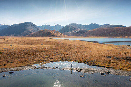 Hiker Crossing a Stream in Mountain Valley