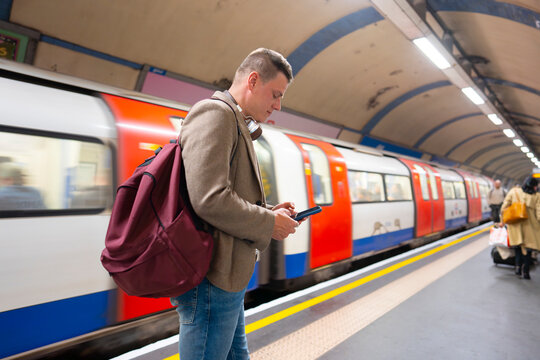 Man using smartphone on subway platform