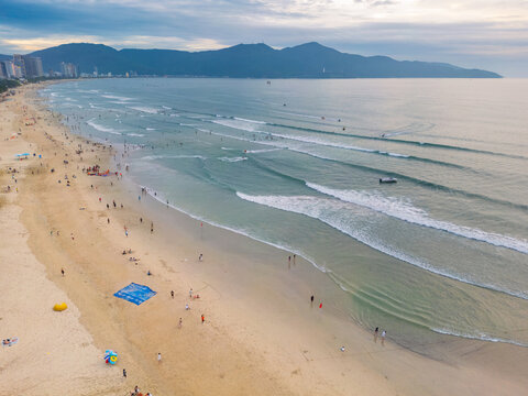 Waves rolling onto a wide sandy beach covered in people