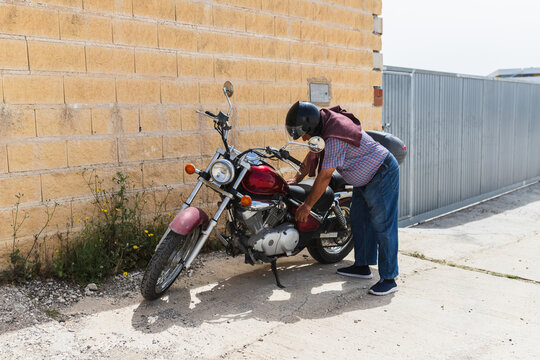Senior Rider Checking Red Cruiser Motorcycle