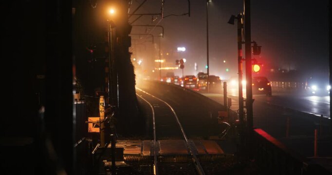 Bright headlight of train on wet racks approaching head on during rain storm in Japanese costal town