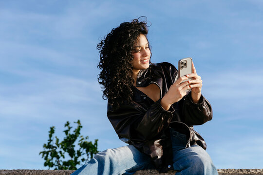 Woman using smartphone under blue sky