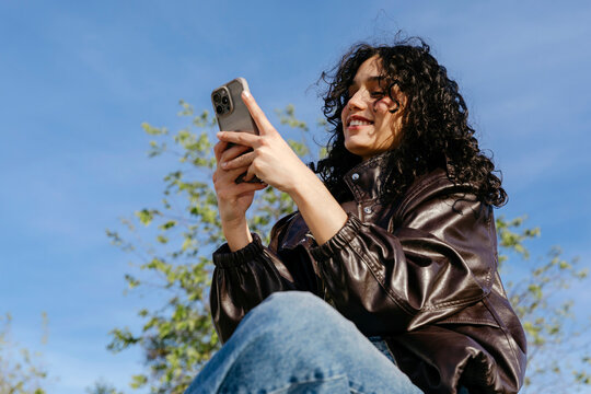 Woman smiling using smartphone outdoors