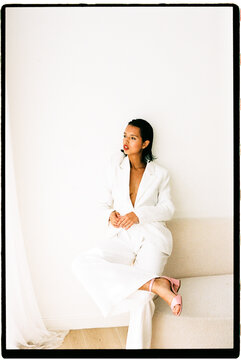 Woman in white suit sitting looking away