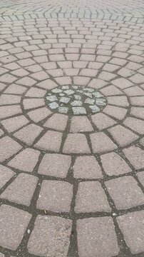 Top view paving stones circular mosaic, closeup overhead shot of concentric cobble rings with beige tiles, gravel filled joints