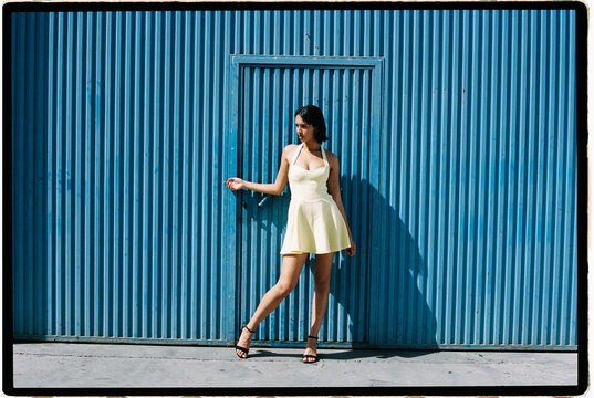 Woman in yellow dress by blue wall