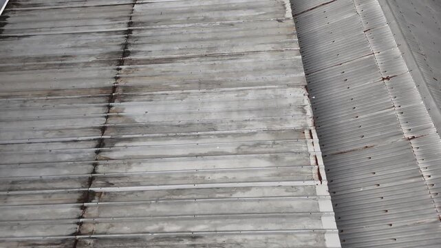 A scene showing a weathered corrugated metal roof with rust stains and an industrial texture, viewed from above.