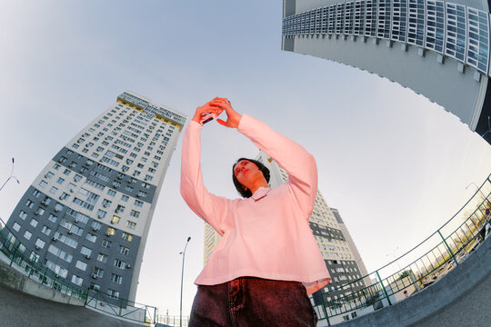 Person Takes Selfie in City Area With Tall Buildings Around