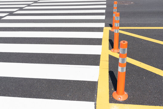 Orange traffic cone beside zebra crossing with yellow lines
