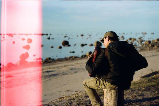 Person sits by the water and plays the accordion.