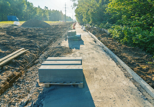 Roadside construction site with stacked concrete curbstones and cleared soil