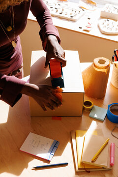 Woman Sealing Box in Small Business Workspace