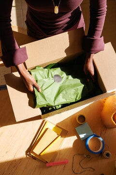 Person packing box with green tissue paper