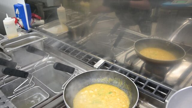 preparazione in una padella nella cucina di un ristorante di un sughetto con mazzancolle frescehe ed un sughetto di pomodorini gialli