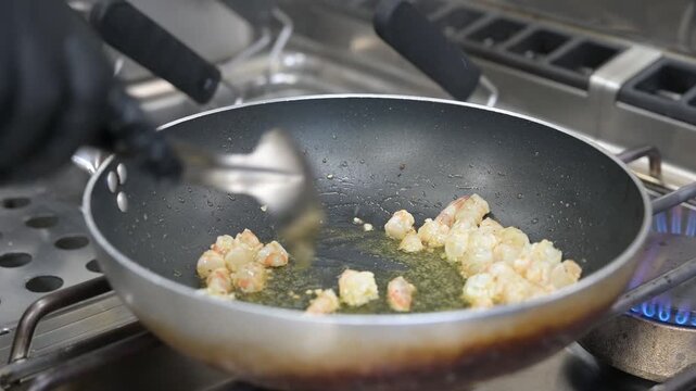 preparazione in una padella nella cucina di un ristorante di un sughetto con mazzancolle frescehe ed un sughetto di pomodorini gialli