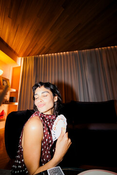 Woman holding cards making a playful expression at home