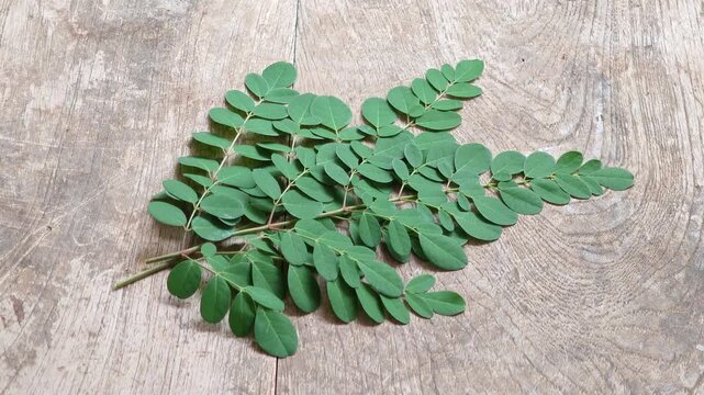 Moringa leaves on an old wooden surface