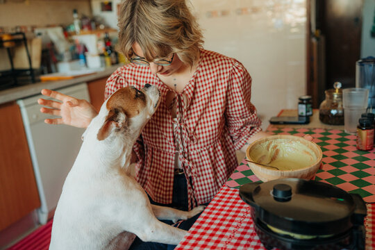 Woman sitting at kitchen table with dog asking for food