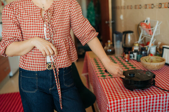 Woman checking waffle maker while cooking at home