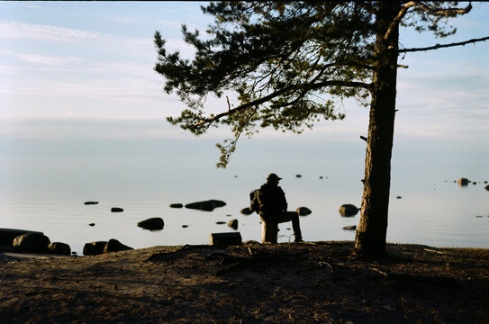 Man sitting by the water at the rocky shore