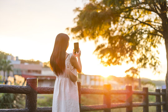 Girl holding smartphone to record beautiful sunset view