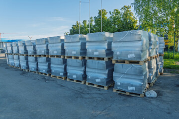 Obraz premium Stacked wrapped pallets of building materials in outdoor storage yard